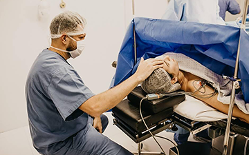 Surgeon carefully positioning a patient's head during preparation for brain tumor surgery in an operating room